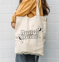 a woman wearing a tote bag with the words new moon