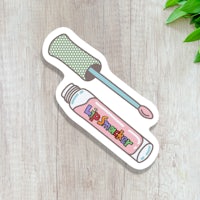 a sticker with a lipstick and a brush