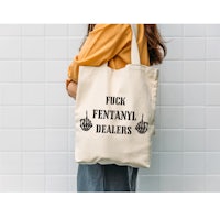 a woman holding a tote bag that says fuck fantasy dealers