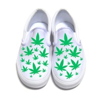 a pair of white slip on shoes with marijuana leaves on them