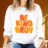 a woman wearing a sweatshirt that says be kind brush