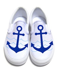 a pair of white slip on shoes with blue anchors on them