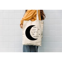 a woman wearing a tote bag with a crescent on it