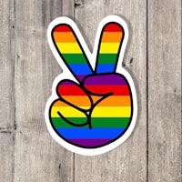 a rainbow peace sign sticker on a wooden background