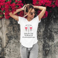 a woman wearing a white t - shirt leaning against a wall with flowers